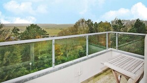Un balcon offrant une vue dégagée sur un paysage verdoyant et des arbres.