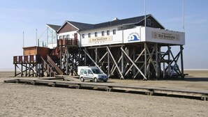 Une structure de jetée en bois abritant un restaurant appelé « Die Seekiste » et un panneau indiquant « St. Peter-Orde ».