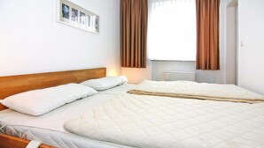 Un lit bien fait, avec une tête de lit en bois, un oreiller blanc et une couverture matelassée.