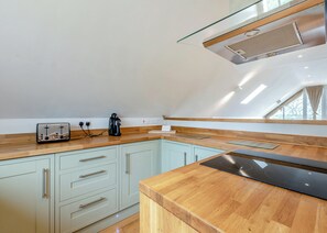 A modern kitchen with a wooden countertop, a toaster, a coffee maker, and a built-in stove.
