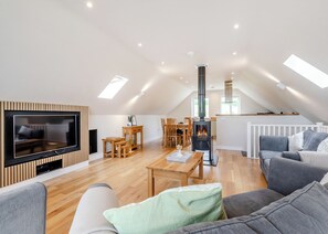 A spacious living area with a TV, wooden furniture, a fireplace, and a dining area.