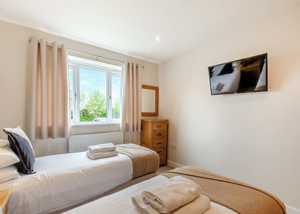 Une chambre avec deux lits, une commode, un miroir et un téléviseur.