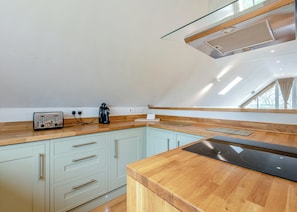 Une cuisine moderne dotée d’un plan de travail en bois, d’un grille-pain, d’une machine à café et d’une cuisinière intégrée.
