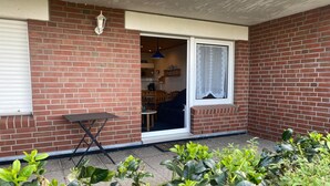 A brick exterior with a sliding glass door leading to a patio area. - Ferienwohnung Tiefblick, Dornumersiel (Dornumersiel)