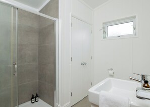 Une salle de bain avec une douche, des toilettes, un lavabo et une fenêtre.