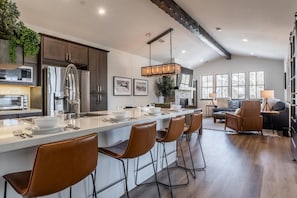 Una cocina moderna con una isla central, electrodomésticos de acero inoxidable y una lámpara colgante.