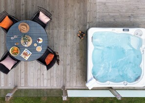 Ein Whirlpool und ein Tisch mit Stühlen und Kissen auf einer Holzterrasse.