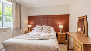 Ein Schlafzimmer mit einem großen Bett, zwei Nachttischen, einem Schminktisch und einem Fenster mit Vorhängen.