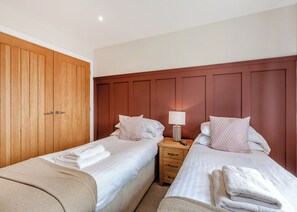 Un dormitorio con dos camas, un armario de madera y una mesita de noche con lámpara.