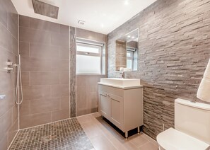 A modern bathroom with a shower, vanity, and toilet.