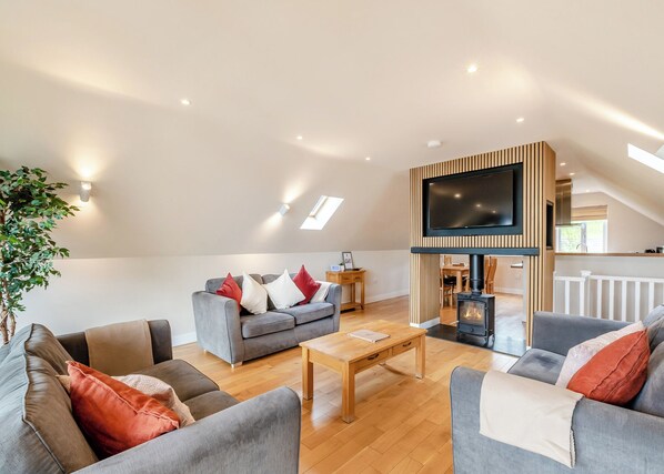 A modern living room with a sofa set, a coffee table, a fireplace, and a TV mounted on a wooden wall.