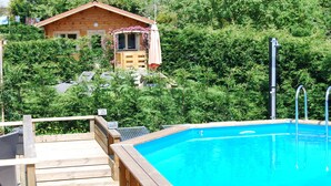Una cabaña de madera con piscina, rodeada de exuberante vegetación.