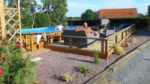 Una terraza de madera con mobiliario exterior y una piscina.