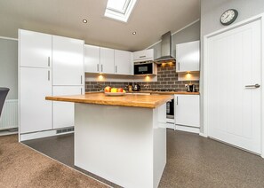A modern kitchen with white cabinetry, a wooden countertop, and a skylight. - Gressingham 50 is a beautiful lodge in a fantastic location. (Carnforth)