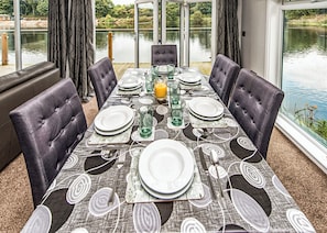 A dining table set for four with a view of a lake. - Gressingham 50 is a beautiful lodge in a fantastic location. (Carnforth)