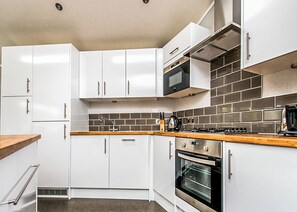 A modern kitchen with white cabinets, a stainless steel oven, a microwave, and a tiled backsplash.