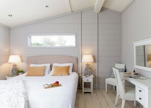 Ein Schlafzimmer mit Bett, Nachttischen, Schreibtisch, Stuhl und Spiegel.
