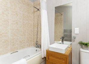 Une salle de bain moderne équipée d’une baignoire, d’une douche, d’un meuble-lavabo et d’un miroir.