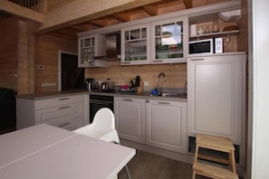 Compact kitchen with central island, sink, stove, and cabinets with glass doors.
