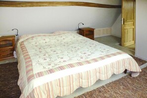 A bedroom with a bed, two bedside tables, a wooden door, and a carpeted floor. - Cottage in Normandy near Alabaster Coast (Crasville-la-Roquefort)
