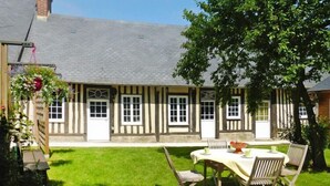 Un edificio tradicional con entramado de madera y un pequeño patio jardín con mesa y sillas.