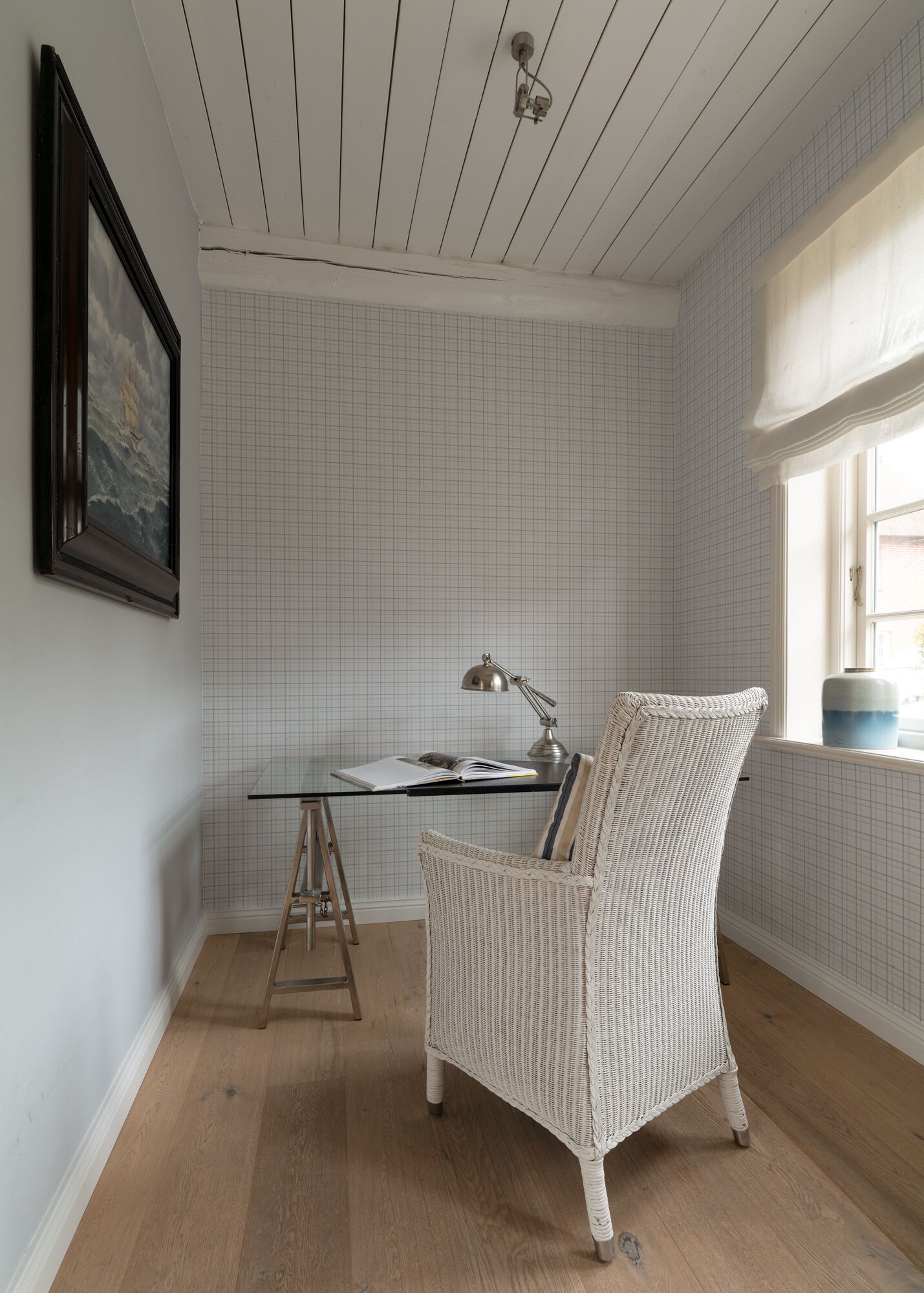 Ein Zimmer mit Schreibtisch, Stuhl und einem Bild an der Wand.