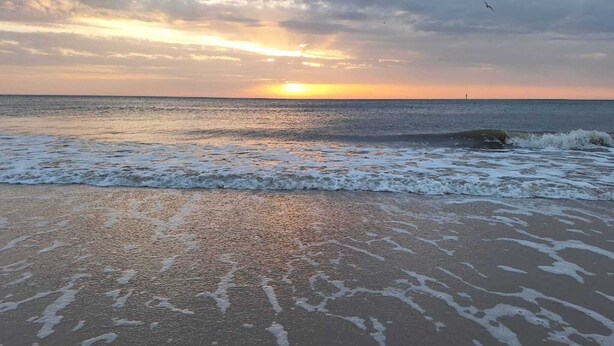 A beach with waves and a sunset in the background. - Ferienwohnung in Westerland auf Sylt (Westerland)