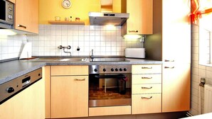Una cocina con armarios de madera, horno de acero inoxidable, microondas y un reloj en la pared.
