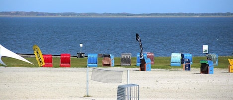A beach with numbered beach huts and a netted area in the foreground.