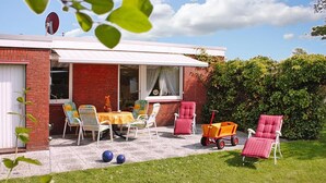 Un patio con mobiliario exterior, una mesa y un área cubierta.