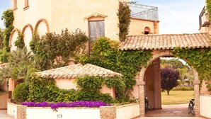 A building with arched windows, a tiled roof, and a covered entrance. - 1 bedroom cozy apartment in Pula (CA) (Pula (CA))
