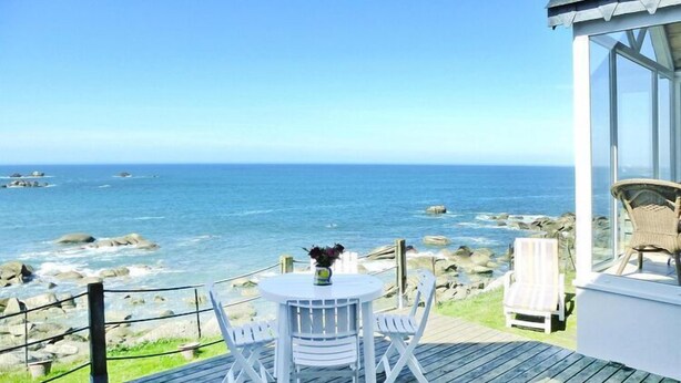 A wooden deck with a table and chairs overlooking the ocean. - Fisherman's House in Brittany by the Sea (Plouescat)