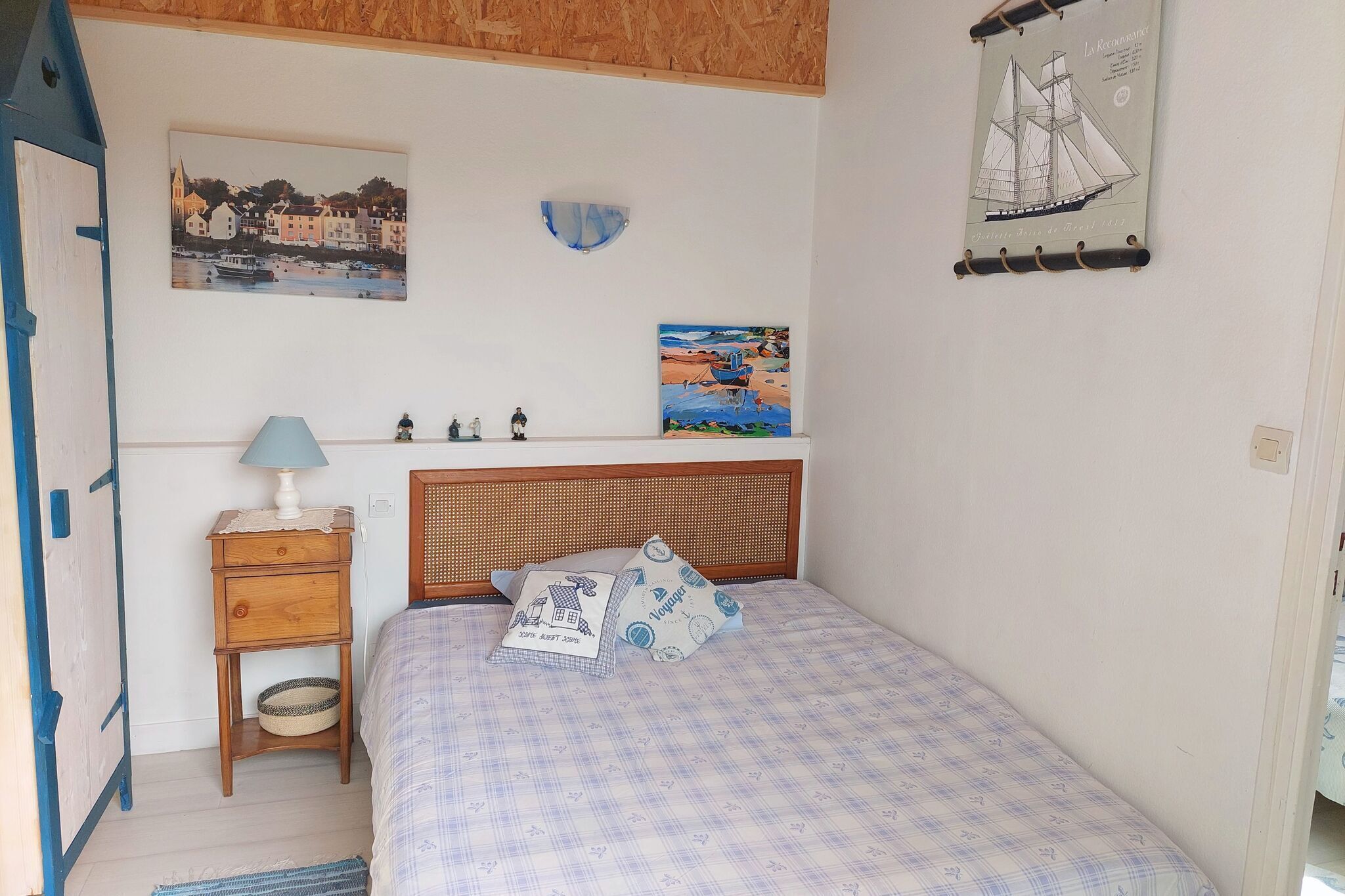 A bedroom with a bed, a nightstand, a lamp, and wall art.