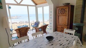 A dining area with a table set for two, overlooking a beach. - Fisherman's House in Brittany by the Sea (Plouescat)