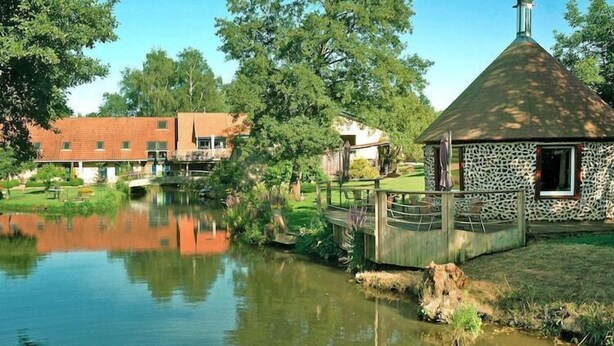 A lakeside property with a small house, a wooden dock, and a bridge over a calm pond. - Holiday Farm by Red River with Indoor Pool (Kindwiller)