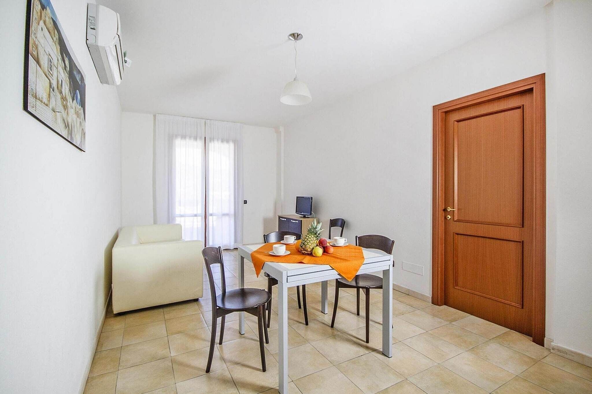 Una habitación compacta con una mesa de comedor, sillas, un sofá, un televisor y una puerta de madera.