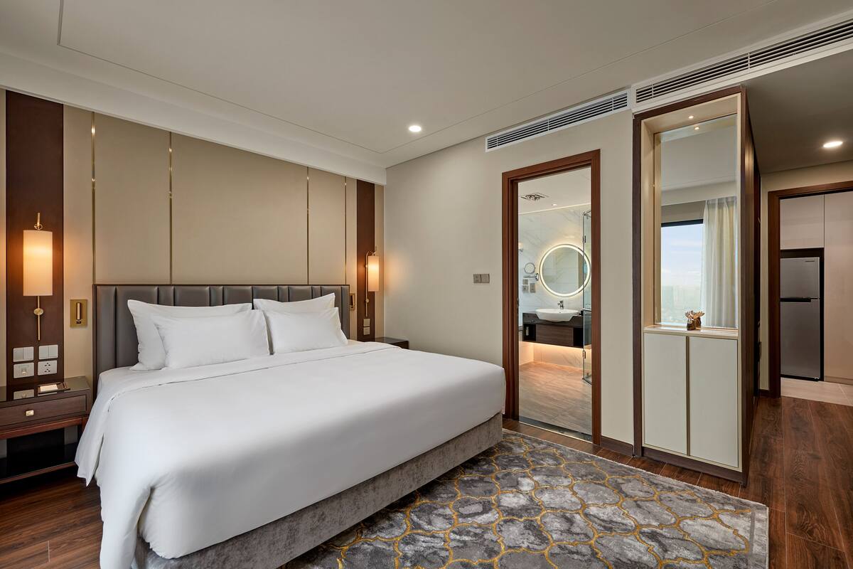 Une chambre d’hôtel moderne avec un grand lit, une salle de bain avec un miroir et une kitchenette.