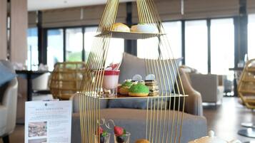A table with a tea set, a menu, and a decorative birdcage containing pastries.
