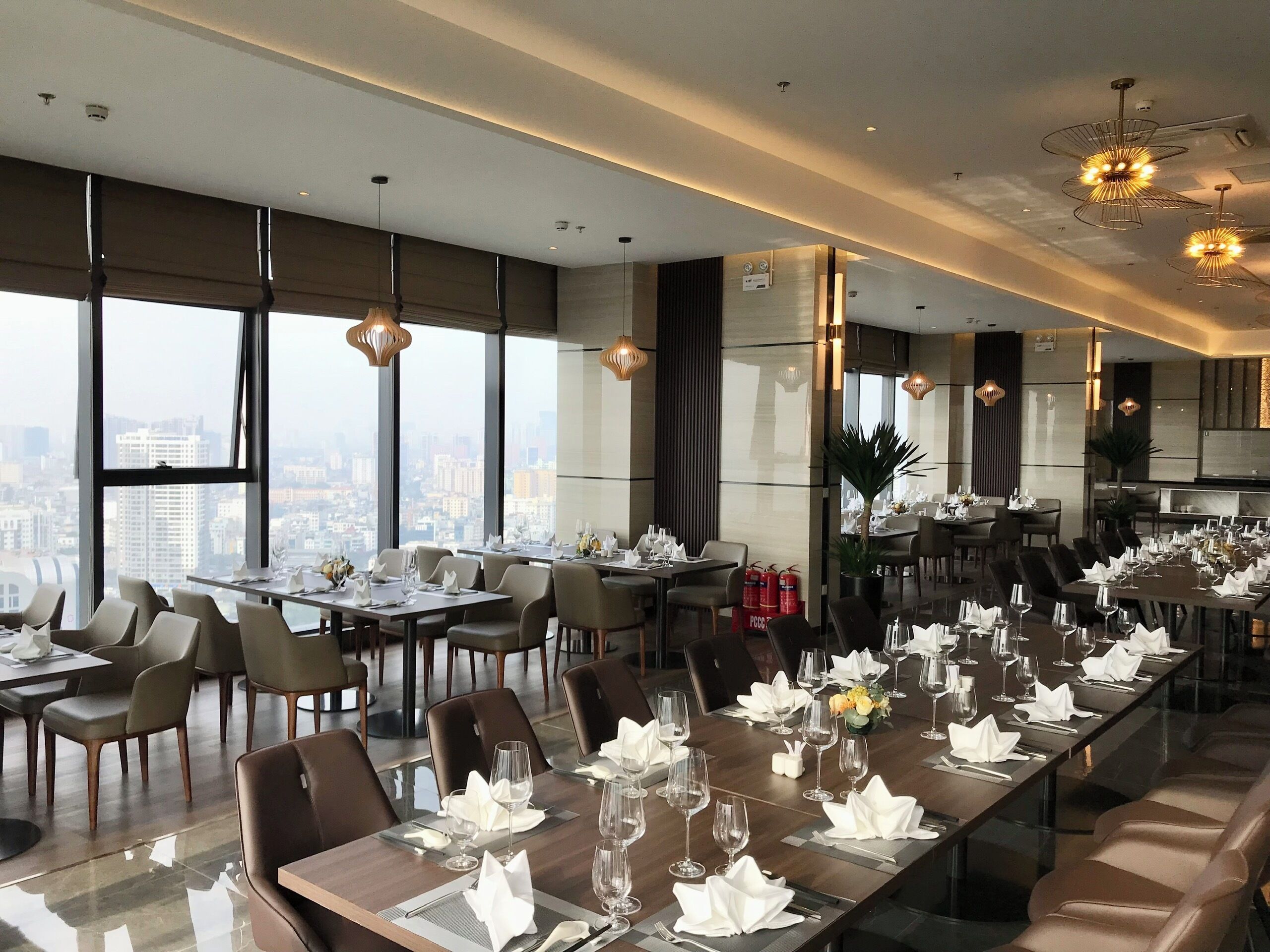 Un espace de restauration moderne doté de grandes fenêtres, de hauts plafonds et de luminaires contemporains.