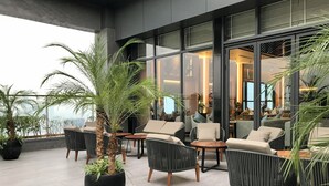 A modern outdoor seating area with wicker furniture and potted plants.