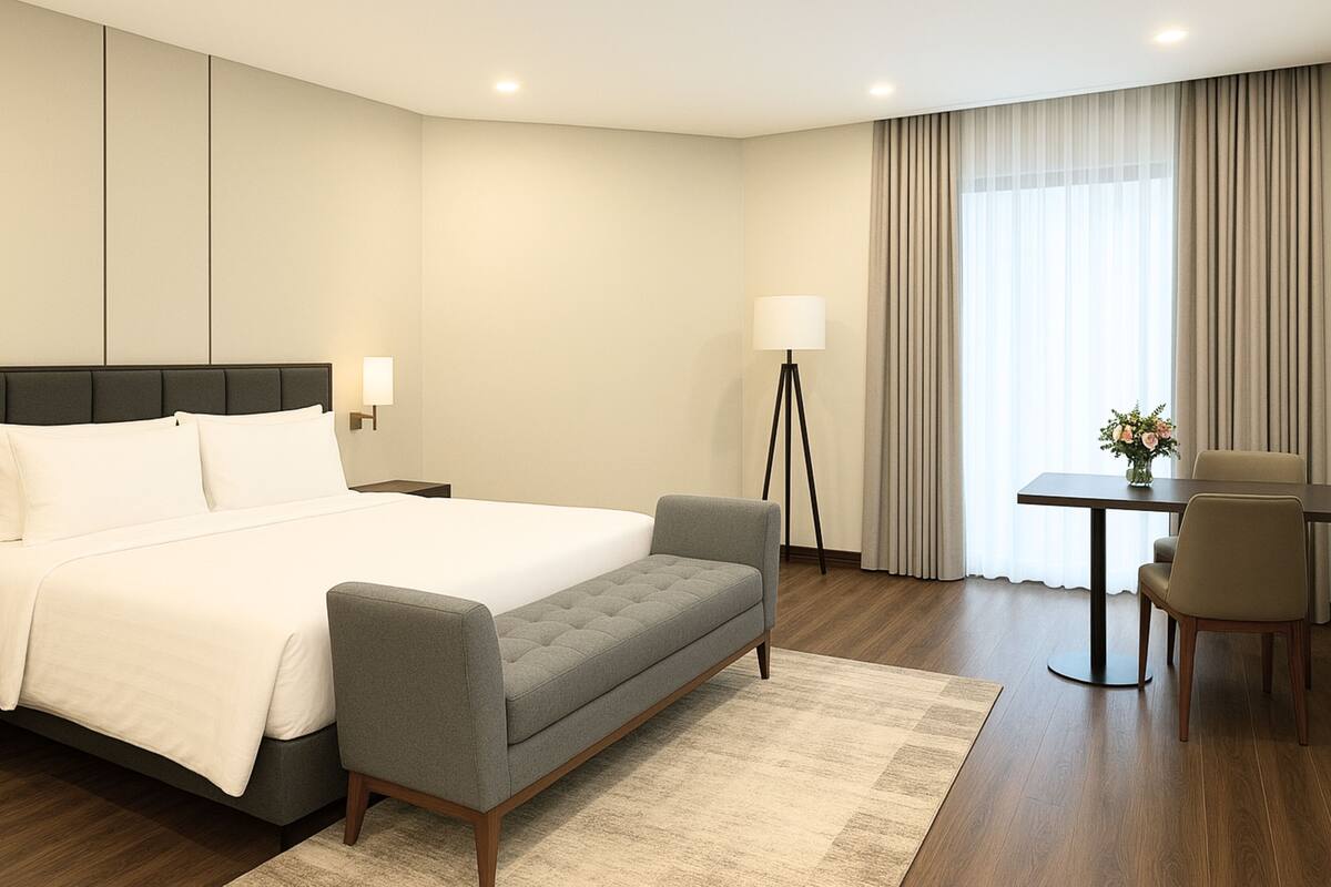 Une chambre d’hôtel avec un grand lit, des tables de chevet, un bureau, une chaise, une lampe sur pied et une fenêtre avec des rideaux.