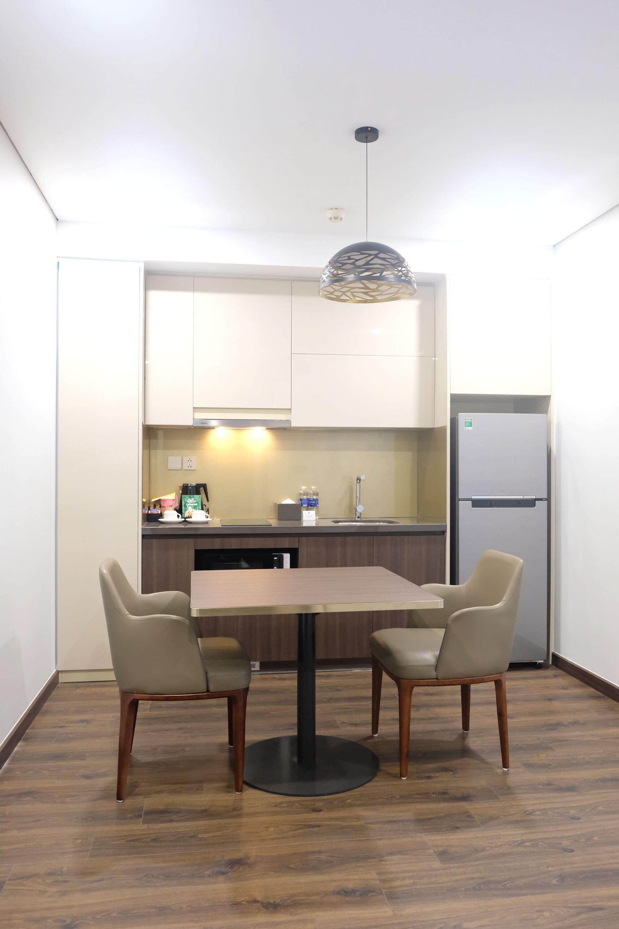 Una cocina compacta con una mesa y sillas, un refrigerador y una cafetera.