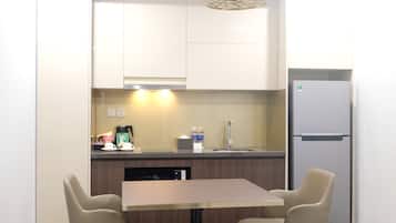 Una cocina compacta con una mesa y sillas, un refrigerador y una cafetera.