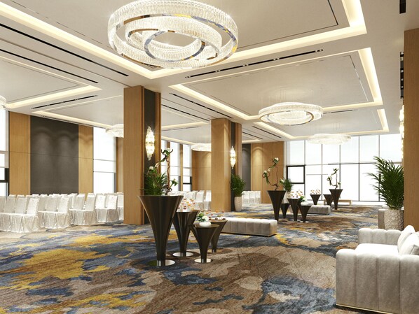 A spacious hotel lobby with a large carpeted area, multiple seating arrangements, and elegant chandeliers.