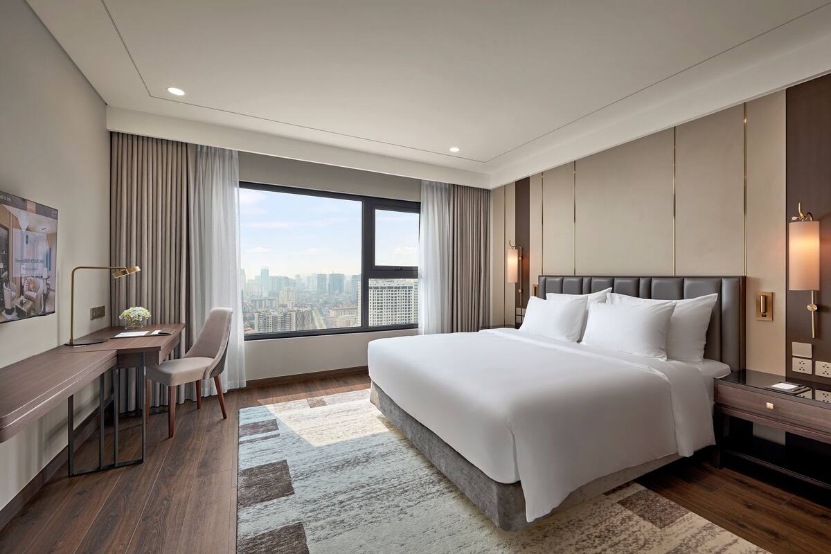 Une chambre d’hôtel moderne avec un grand lit, un bureau et une vue sur la ville.