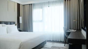 A hotel room with a large bed, a desk, and a TV.