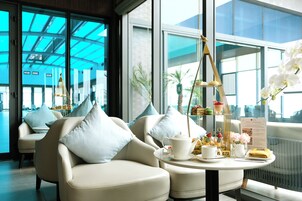 A modern hotel room with a seating area featuring two sofas and a round table with a tea set.