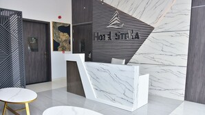 Un'area reception moderna con una scrivania in marmo, un logo a parete e un motivo decorativo sul muro.