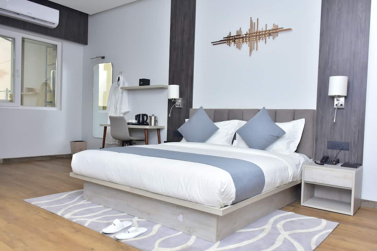 Un dormitorio moderno con una cama grande, mesitas de noche, un escritorio y un espejo.