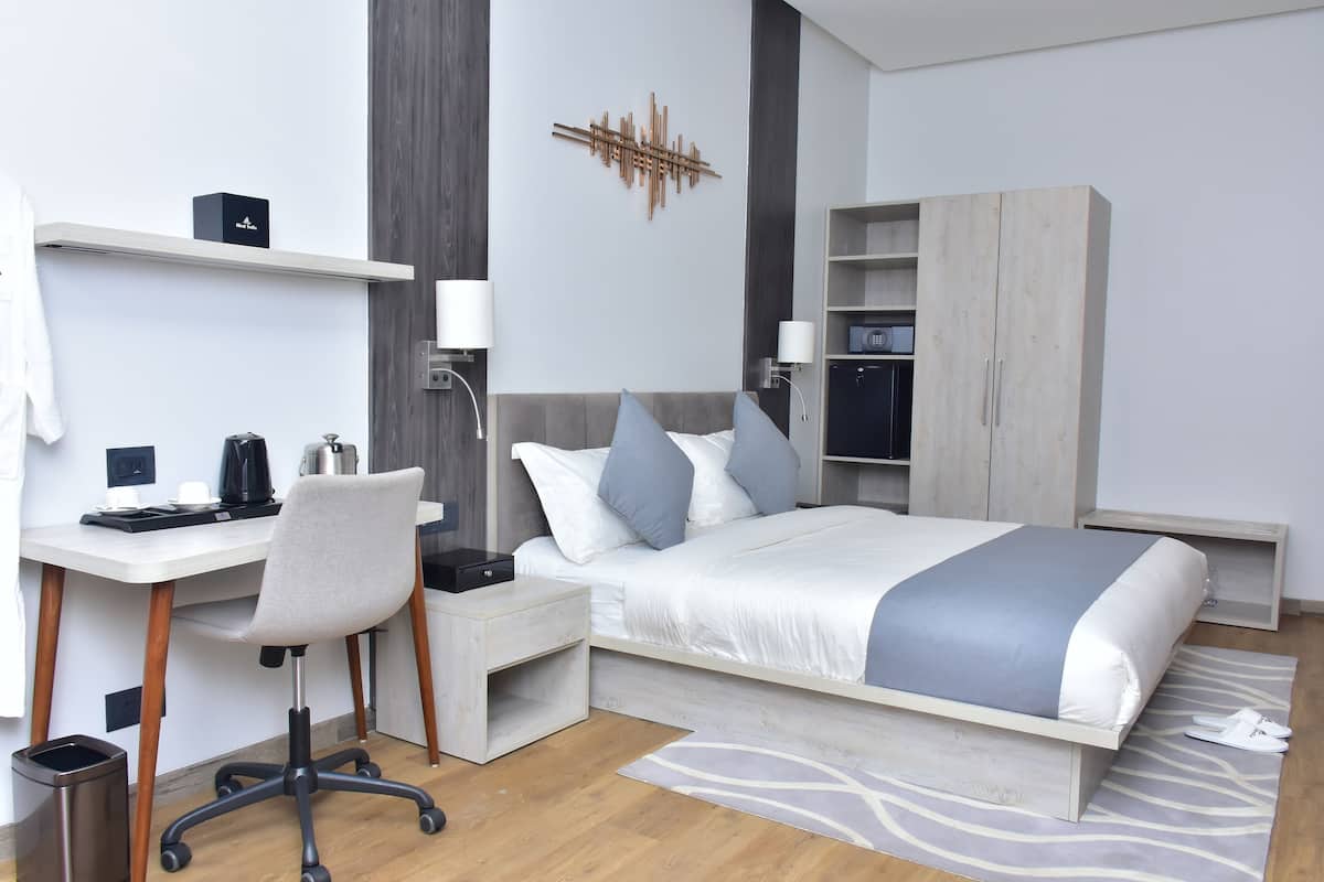 Una habitación de hotel moderna con cama, escritorio, silla y armario.